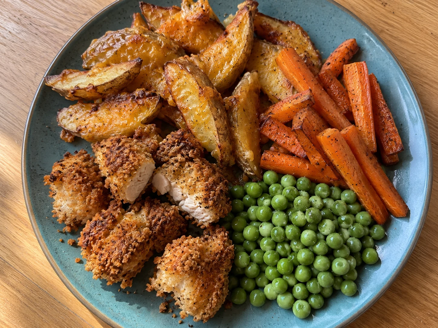 Mild Cajun Chicken Bites with cheesy wedges, roast carrots and peas.